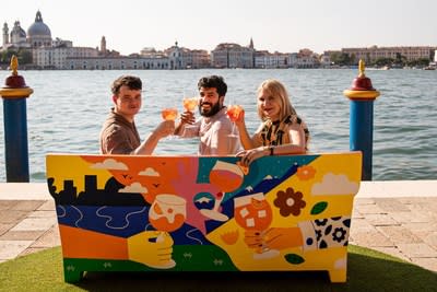 Three artists pose with their collaborative piece of urban art, a sofa celebrating Aperol’s centenary and role in sparking joyful connections