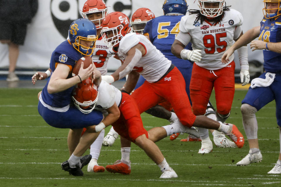Sam Houston State defenders tackle South South Dakota State place kicker Cole Frahm, front left, after a fumble on a field goal-attempt during the first half of the NCAA college FCS Football Championship in Frisco, Texas, Sunday, May 16, 2021. (AP Photo/Michael Ainsworth)