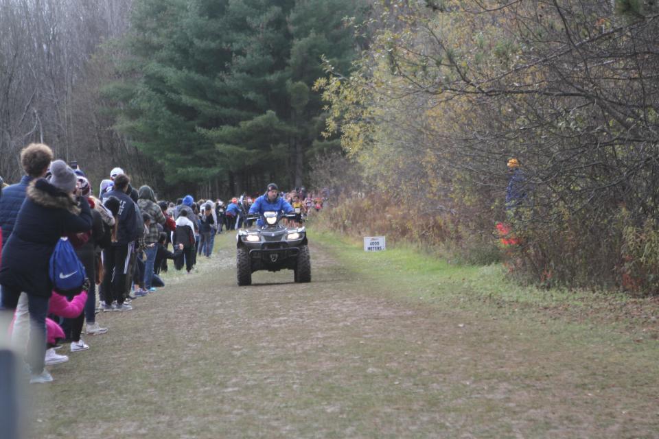 Fans line the course as a four-wheeler is driven ahead of the lead runners in the boys Class B race during the state cross-country championships Nov. 11, 2022 in Verona, New York.