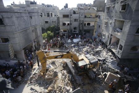 Palestinians gather as rescue workers search for victims under the rubble of a house, which witnesses said was destroyed in an Israeli air strike that killed three senior Hamas military commanders, in Rafah in the southern Gaza Strip August 21, 2014. REUTERS/Ibraheem Abu Mustafa