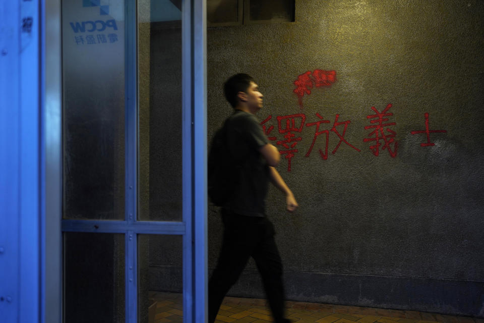 In this Sept. 17, 2019, photo, a man walks past a red anti-government graffiti reads in Chinese "Release righteous" outside a subway station in Hong Kong. As Hong Kong enters its fourth month of steady protests, the city is embracing for another violent weekend prior to the upcoming 70th National Day on Oct. 1. (AP Photo/ Vincent Yu)