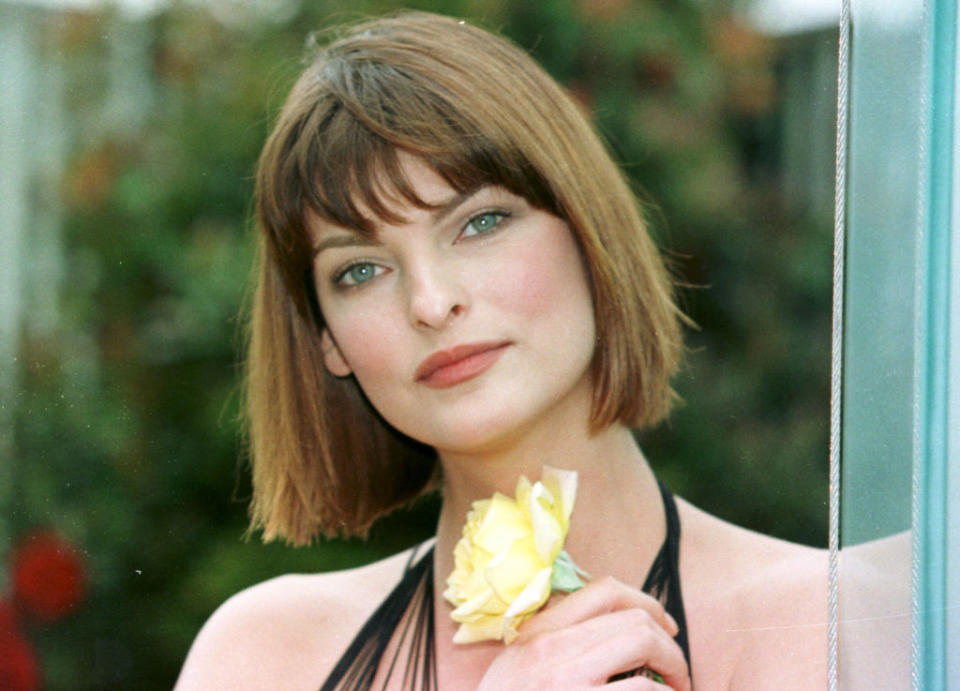 Linda Evangelista posing and holding a flower