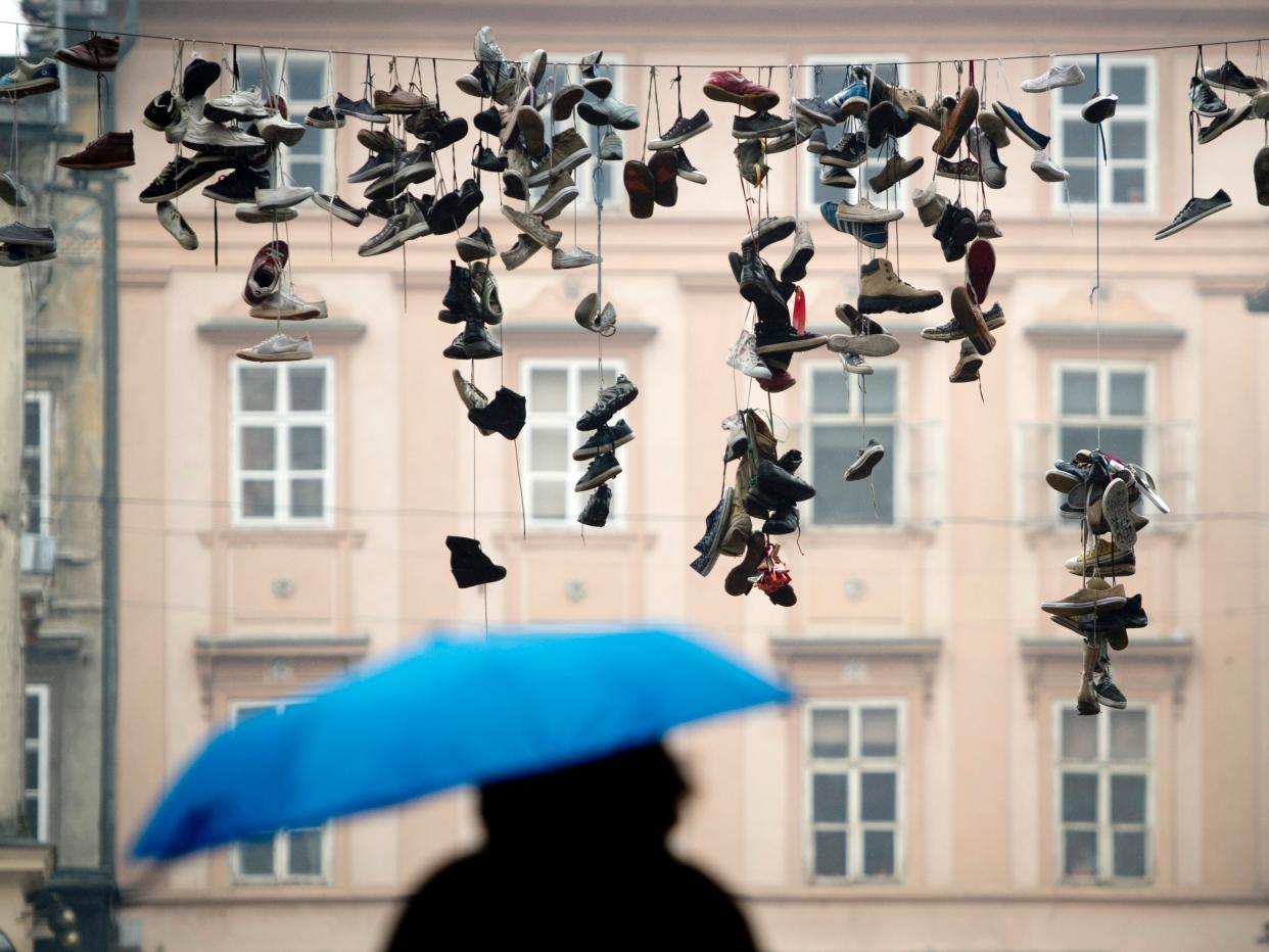 A woman walks underneath shoes hanging from a power line in the centre of the Slovenian capital Ljubljana on March 6, 2013. (ODD ANDERSEN/AFP via Getty Images)