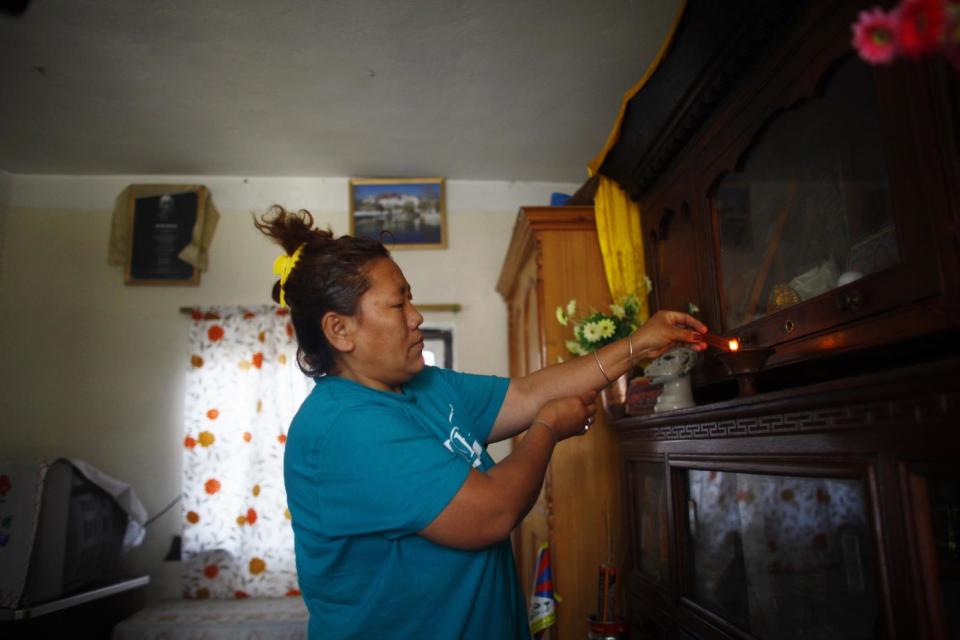 In this Wednesday, April 2, 2014 photo, a Tibetan refugee Sonam Chodon lights incense sticks inside her home at the Tibetan refugee camp in Katmandu, Nepal. Chodon said she and another Tibetan Sonam Tashi were held for weeks after being picked up by police who broke up a small rally in front of the Chinese Embassy visa office on March 10 and were released only this week without charges or access to legal aid in a sign that authorities are bowing to pressure from China. The government on Thursday denied accusations in a report by Human Rights Watch that it is mistreating Tibetans. Nearly 20,000 Tibetans who fled their homeland now live in Nepal. (AP Photo/Niranjan Shrestha)