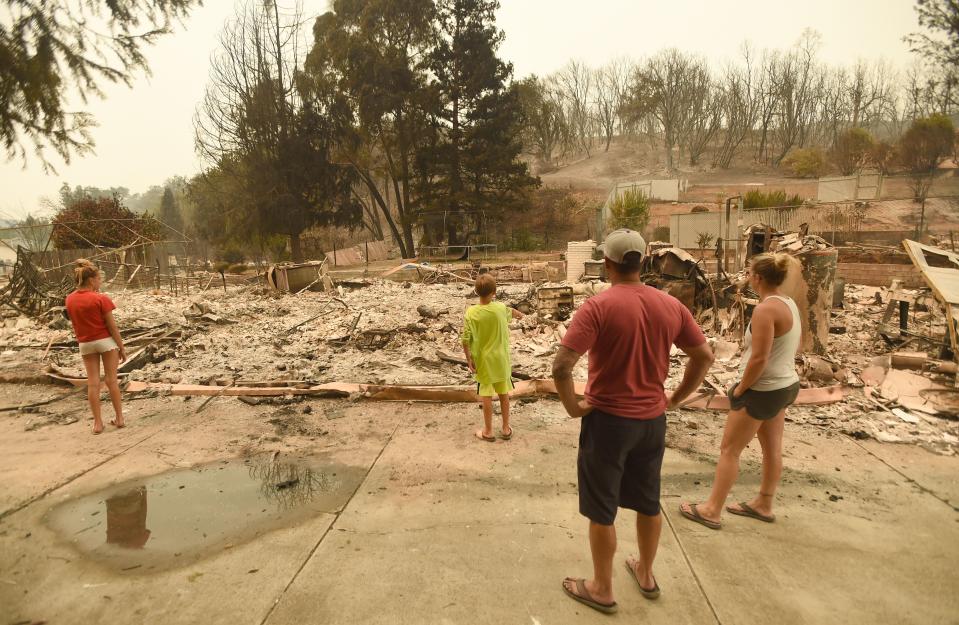 Wade Brilz looks at his burned home with his family during the Carr fire in Redding, California on July 27, 2018.