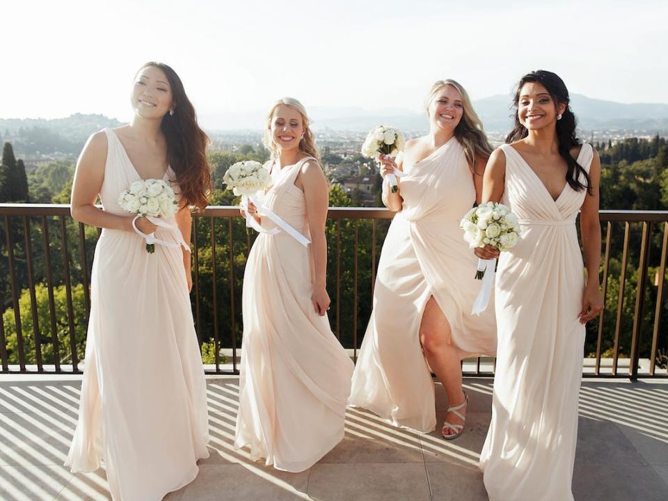 Bridesmaids wearing white dresses and holding white floral bouquets