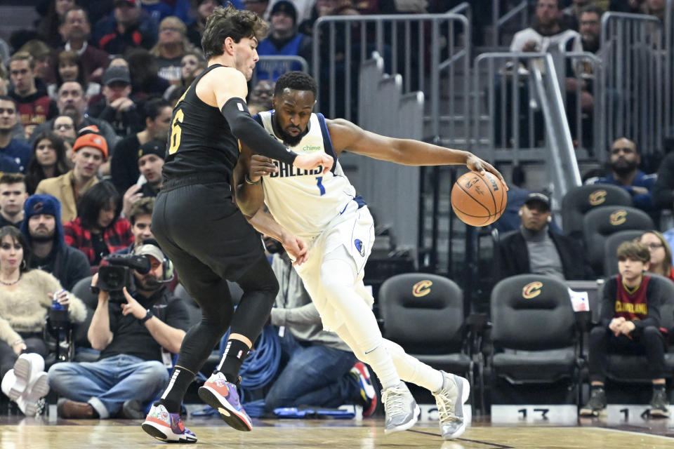 Dallas Mavericks guard Theo Pinson, right, drives against Cleveland Cavaliers forward Cedi Osman, left, during the first half of an NBA basketball game, Saturday, Dec. 17, 2022, in Cleveland. (AP Photo/Nick Cammett)