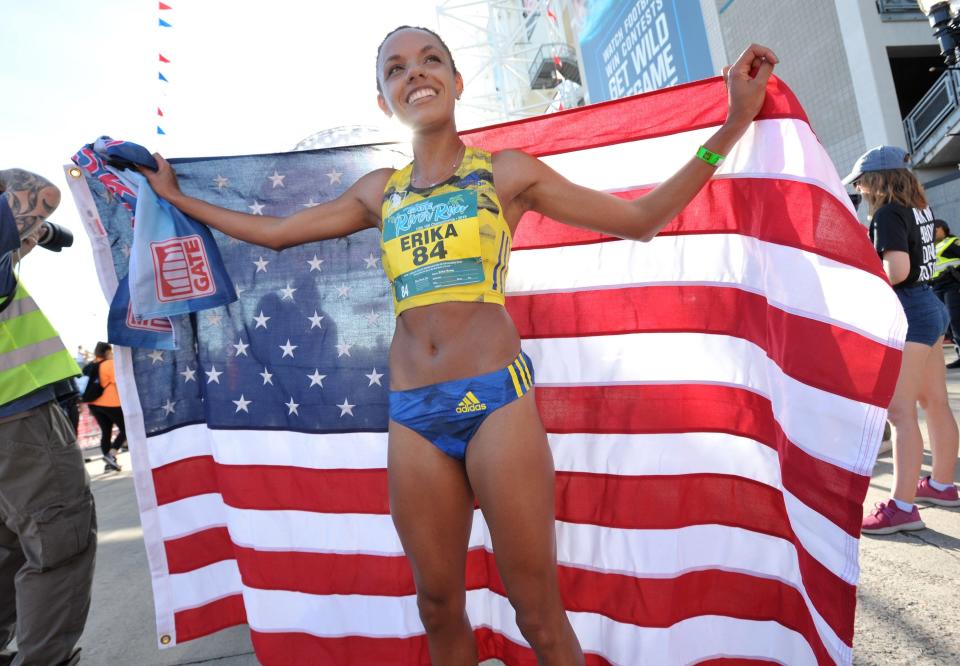 Top women's finisher Erika Kemp displays the American flag after crossing the finish line of the 2019 Gate River Run.