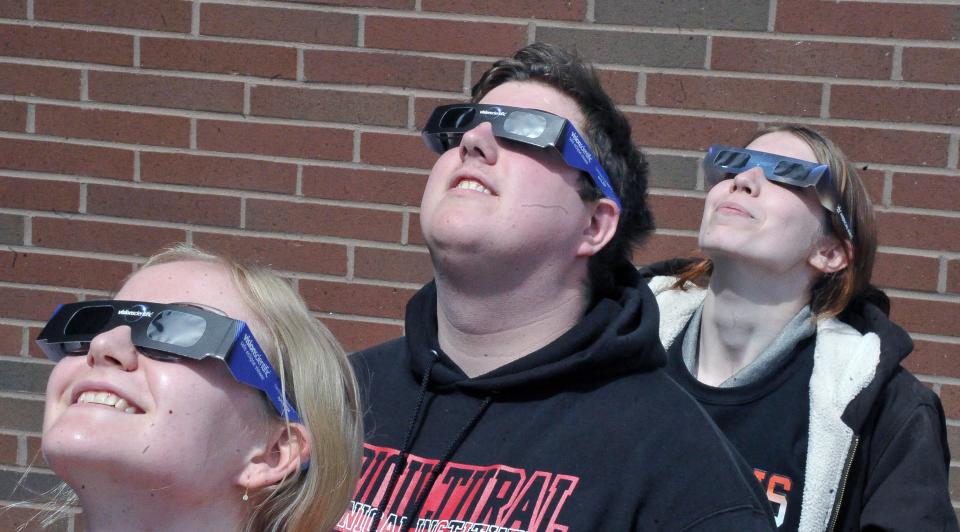 Hanna Warnecke, Columbus, Zachary Zimardi, Youngstown and Blair Butler of Newcomerstown get a quick look at the solar eclipse progress.