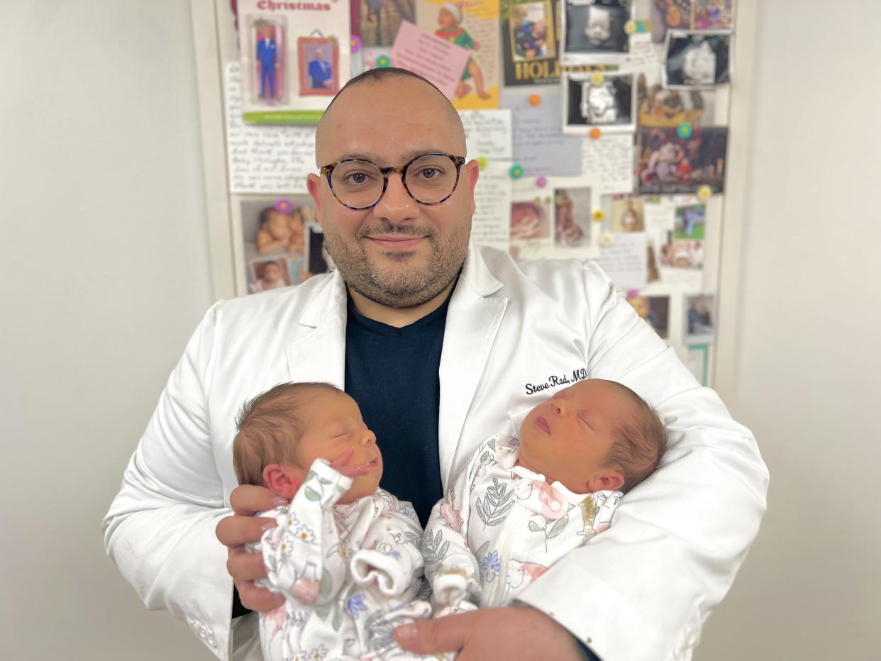 Dr. Steve Rad of the Ari Rubin Rainbow Clinic holds twin babies in his arms.