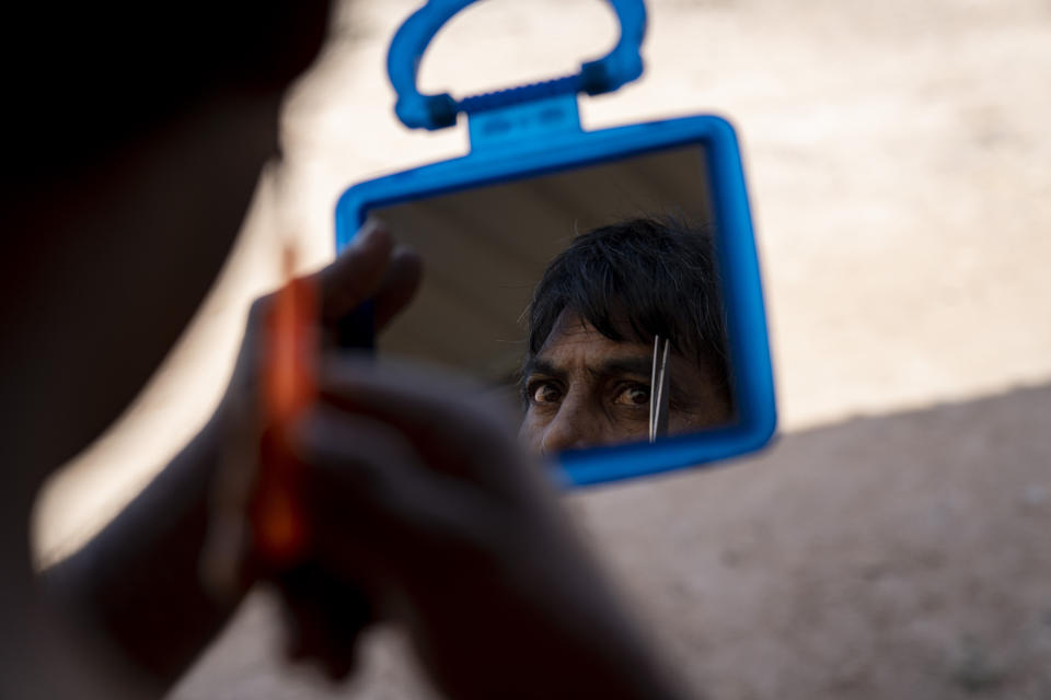 A migrant worker trims his eyebrows at his living quarters on a palm oil plantation run by government-owned Felda in Malaysia in early 2020. Jum, a former worker who escaped from this same plantation, described to The Associated Press how the company confiscated and later lost his Indonesian passport, leaving him vulnerable to arrest and forcing him to hide in the jungle. (AP Photo/Ore Huiying)