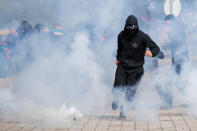 A man runs away from tear gas during clashes with French riot police during a demonstration against the government's labour reforms in Nantes, France, September 21, 2017. REUTERS/Stephane Mahe