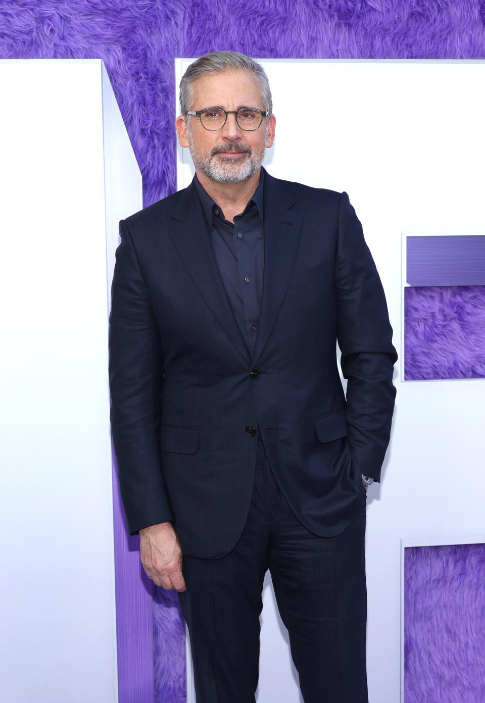 Steve Carell in a black, pinstripe suit and glasses at an event