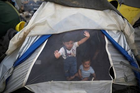 Children look out from a tent at a makeshift camp for migrants and refugees at the Greek-Macedonian border near the village of Idomeni, Greece, April 1, 2016. REUTERS/Marko Djurica