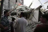 Palestinians stand by the rubble of the home of Hamas Gaza leader Ismail Haniyeh, which Gaza's interior ministry said was hit by a missile fired by Israeli aircraft before dawn on Tuesday, causing damage but no casualties, in Gaza City July 29, 2014. REUTERS/Finbarr O'Reilly