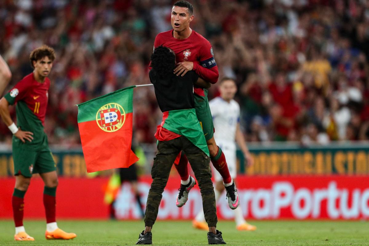 Cristiano Ronaldo é carregado por um torcedor enquanto corre para o campo durante as eliminatórias da Eurocopa de Portugal