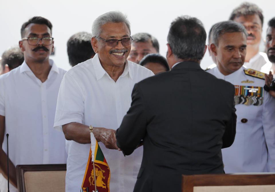 Sri Lanka's newly elected president Gotabaya Rajapaksa, second left, greets as he takes the oath of office in front of chief justice Jayantha Jayasuriya, back to camera as his son Manoj, left, watches during the swearing in ceremony held at the 140 B.C Ruwanweli Seya Buddhist temple in ancient kingdom of Anuradhapura in north central Sri Lanka Monday, Nov. 18, 2019. The former defense official credited with ending a long civil war was Monday sworn in as Sri Lanka’s seventh president after comfortably winning last Saturday’s presidential election. (AP Photo/Eranga Jayawardena)