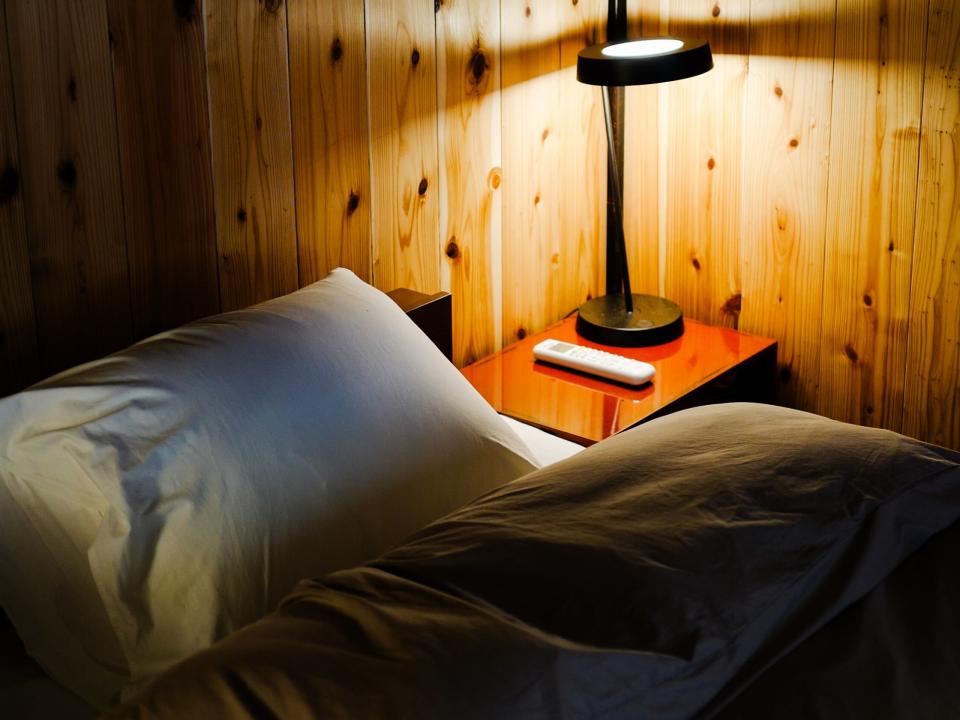 a bed in a wooden room next to a lamp