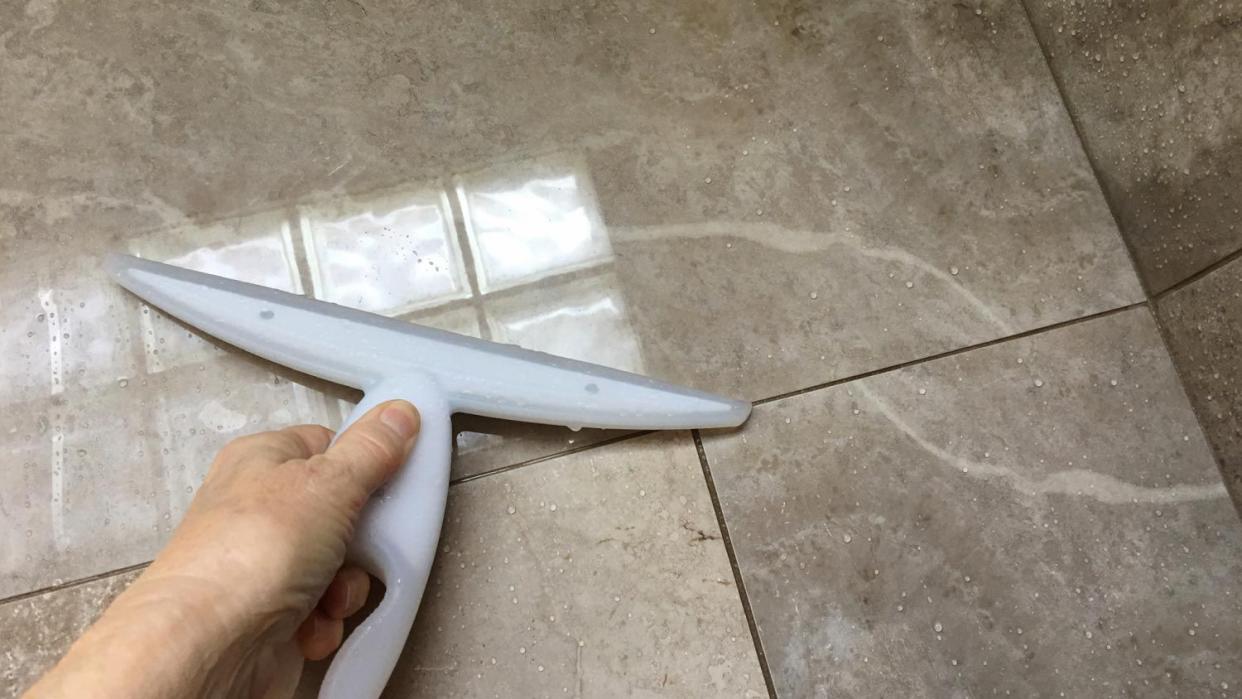 Cleaning a tiled shower with a squeegee