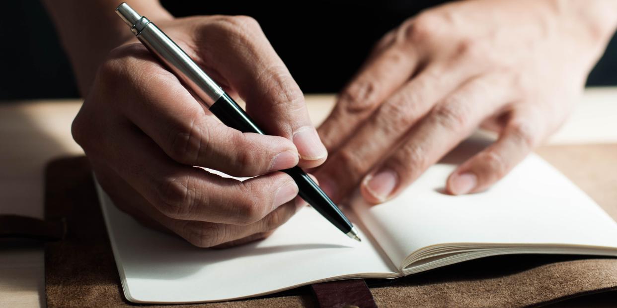 Close-up of man writing in a notebook.