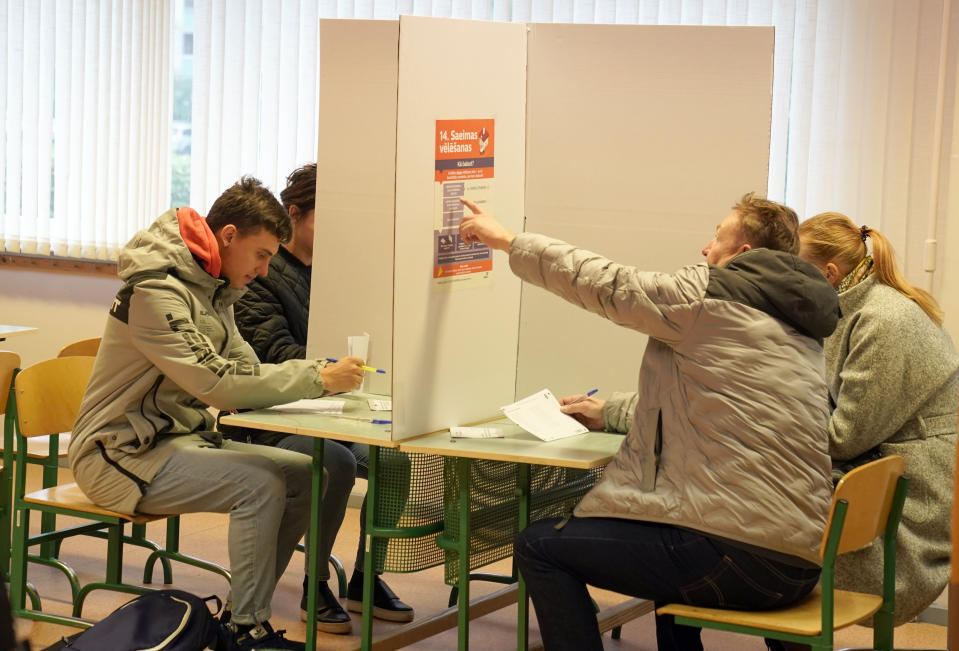 Latvians mark their ballots at a polling station during general elections in Riga, Latvia, Saturday, Oct. 1, 2022. Polling stations opened Saturday in Latvia for a general election influenced by neighboring Russia’s attack on Ukraine, disintegration among the Baltic country’s sizable ethnic-Russian minority and the economy, particularly high energy prices. (AP Photo/Roman Koksarov)