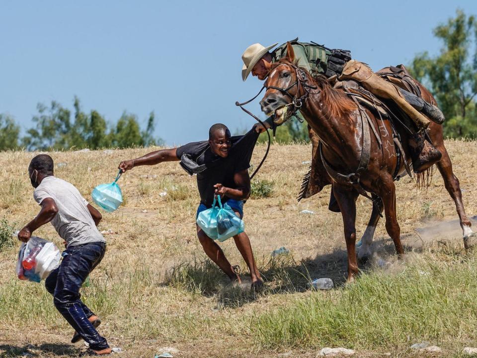 A US Border Patrol agent on horseback grabbing a Haitian migrant.