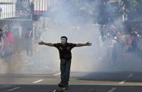 Un manifestante enmascarado abre sus brazos durante una protesta en Caracas contra el gobierno de Venezuela el 20 de marzo de 2014 (AFP/Archivos | Federico Parra)