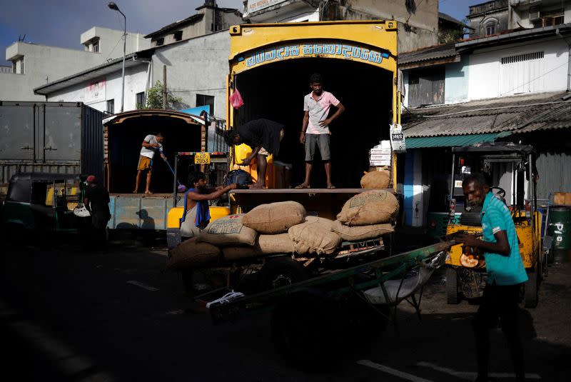 Laborers wait after unloading the sacks of rice at a wholesale market, amid the country's economic crisis in Colombo