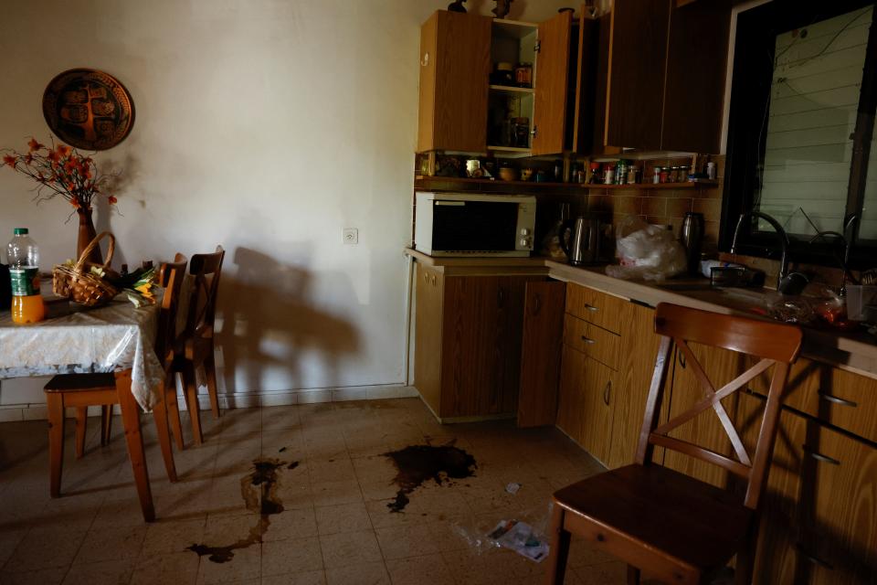 An image of a kitchen with drawers open and puddles of blood on the floor.