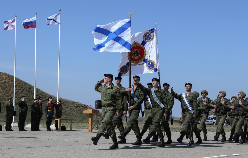 In this photo provided by Russian Defense Ministry shows, Russian Defense Minister Sergei Shoigu, third from left, looks at Russian marines as they march with the Russian navy Sevastopol's flags at a military base in Sevastopol, Crimea, Monday, March 24, 2014. Shoigu's visit comes as Ukraine's fledgling government on Monday ordered Ukrainian troops to withdraw from Crimea, ending days of wavering as Russian troops consolidate control over the peninsula. (AP Photo/Press Service of Russian Defense Ministry, Vadim Savitsky)