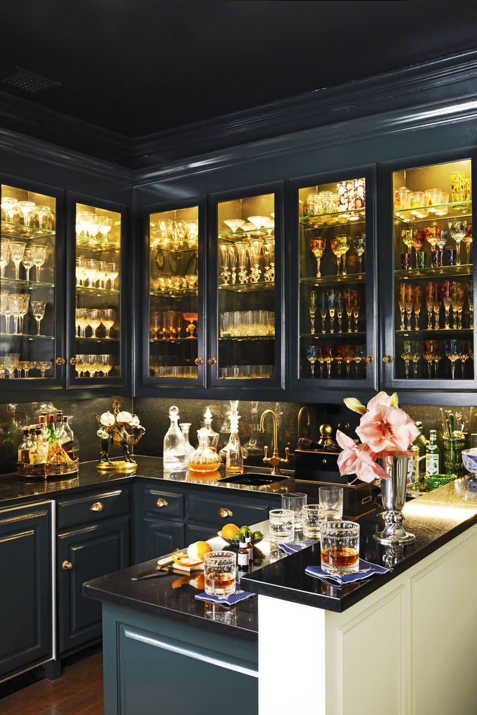 a room with greenish blue cabinets and shelves of liquor