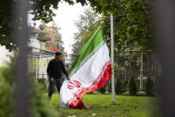 A protester takes down the Iranian flag on the ground of the Iranian embassy during the global protest against the Iranian regime in front of the Iranian embassy in Bern, Switzerland, Saturday, Oct. 1, 2022. They protest against the death of Mahsa Amini, a woman who died while in police custody in Iran. Mahsa Amini was arrested by Iran's morality police for allegedly violating its strictly-enforced dress code. (Peter Klaunzer/Keystone via AP)