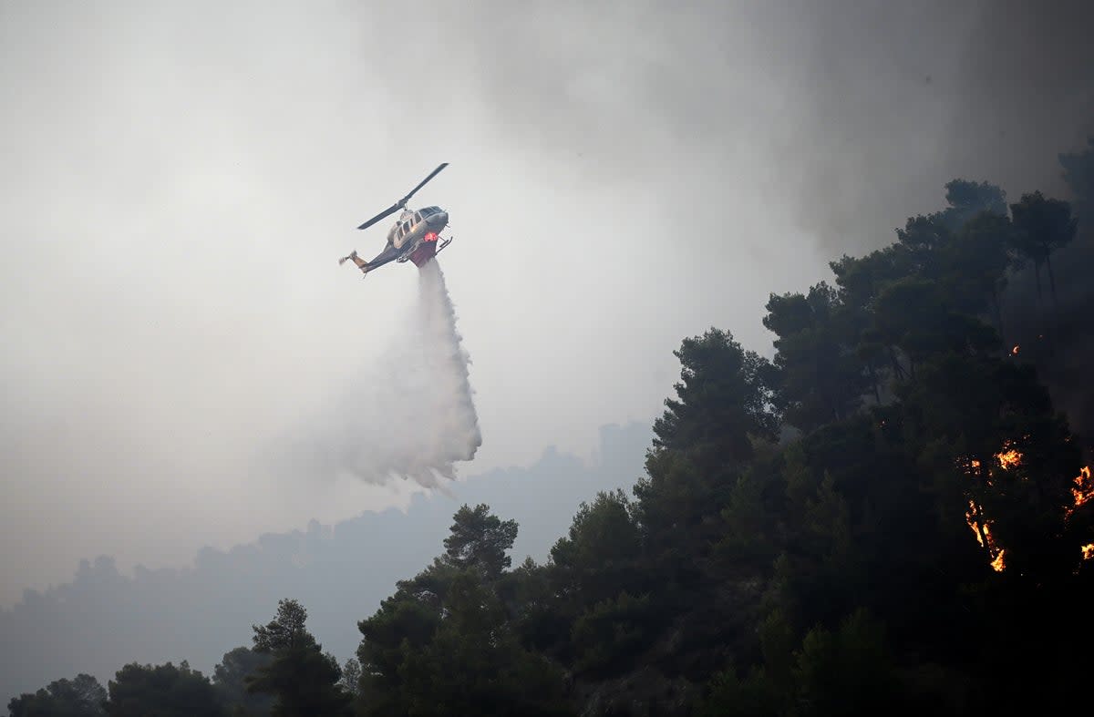 A firefighting helicopter drops water to extinguish a wildfire, in Diakopto, Egio, Greece (EPA)