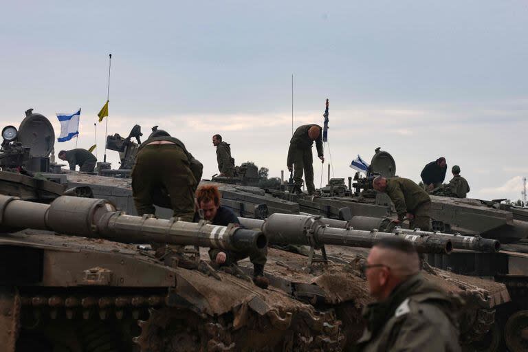 A picture taken from southern Israel along the border with the Gaza Strip shows Israeli soldiers ontop their tanks at a position upon their return from a mission in the Palestinian territory on January 28, 2024, amid ongoing battles between Israel and the Palestinian Hamas militant group. (Photo by Menahem KAHANA / AFP)