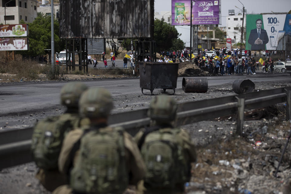 Palestinian demonstrators throws stones during clashes with Israeli security forces at the Hawara checkpoint, south of the West Bank city of Nablus Friday, May 21, 2021. (AP Photo/Majdi Mohammed)