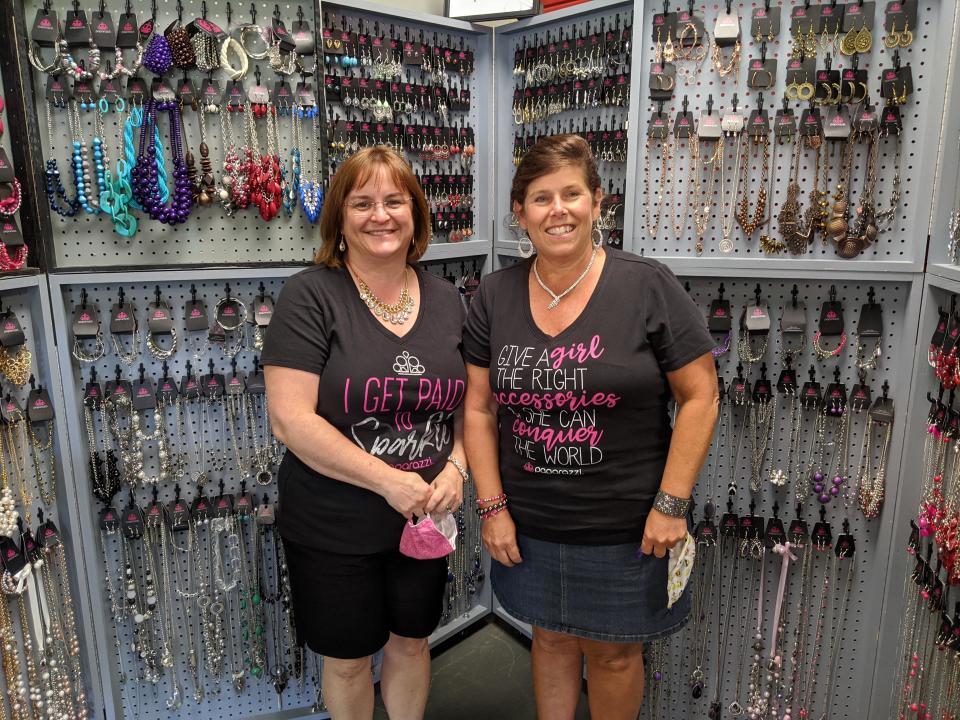 Tracy DeVries (left) and Kim Griffioen (right) pose in front of their Paparazzi Accessories booth at Artisan Markt in Holland Town Center.