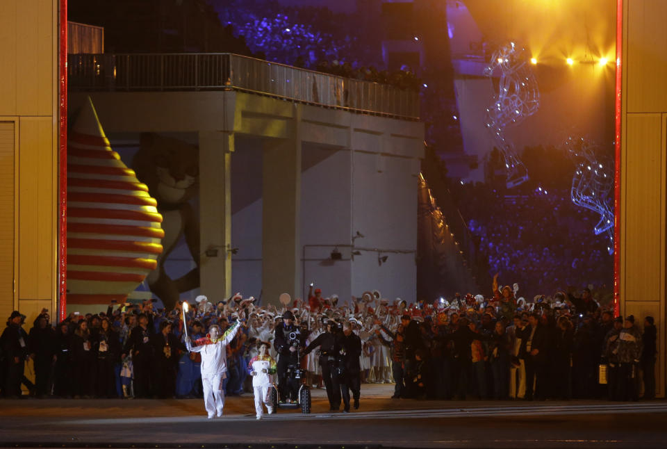 Irina Rodnina and Vladislav Tretiak run before lighting the Olympic cauldron during the opening ceremony of the 2014 Winter Olympics in Sochi, Russia, Friday, Feb. 7, 2014. (AP Photo/Matt Slocum, Pool)