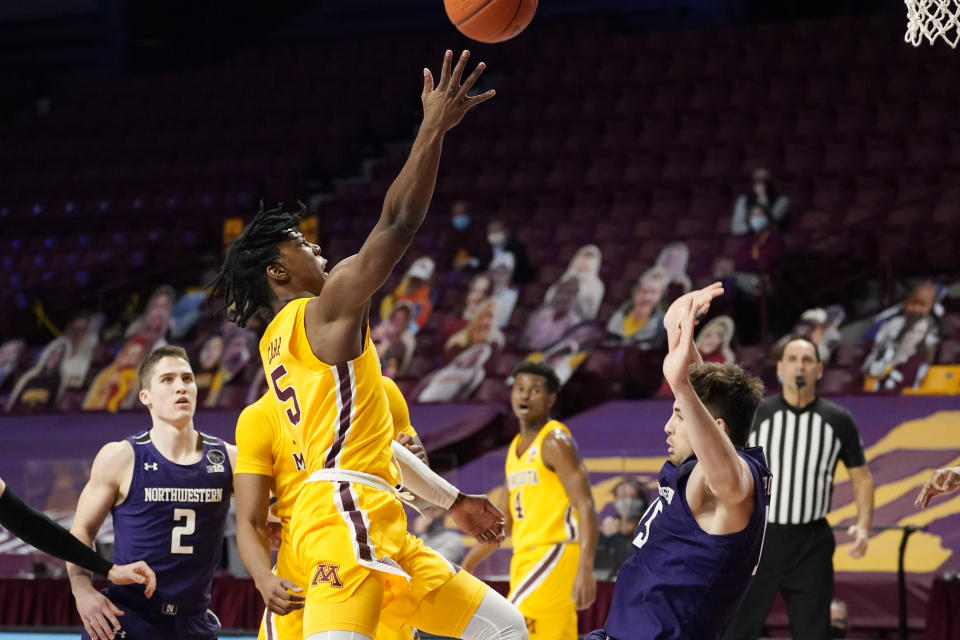 Minnesota's Marcus Carr (5) shoots as Northwestern's Ryan Young, right, falls following a collision with Carr in the first half of an NCAA college basketball game, Thursday, Feb. 25, 2021, in Minneapolis. (AP Photo/Jim Mone)