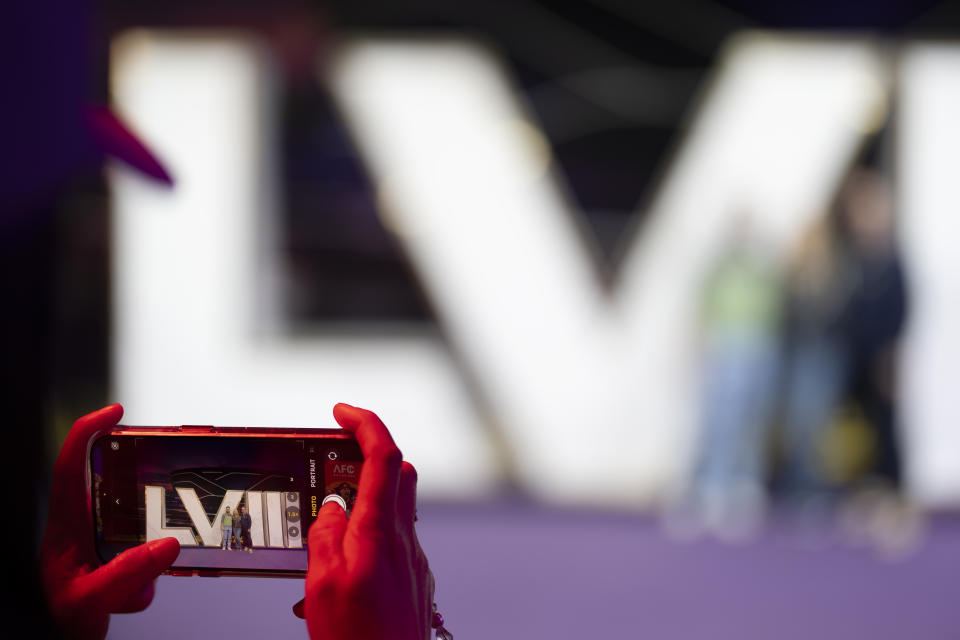 A woman takes a picture of a family posing with an image for the upcoming Super Bowl 58 at NFL Experience, Saturday, Feb. 10, 2024, in Las Vegas. The Kansas City Chiefs will play the NFL football game against the San Francisco 49ers Sunday. (AP Photo/Gregory Bull)