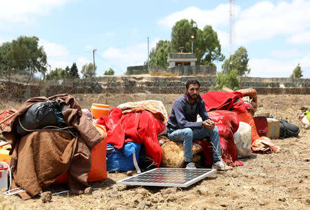 An Internally displaced man sits near belongings in front of a U.N. location near the Israeli-occupied Golan Heights in Quneitra, Syria June 29, 2018. REUTERS/Alaa Al-Faqir