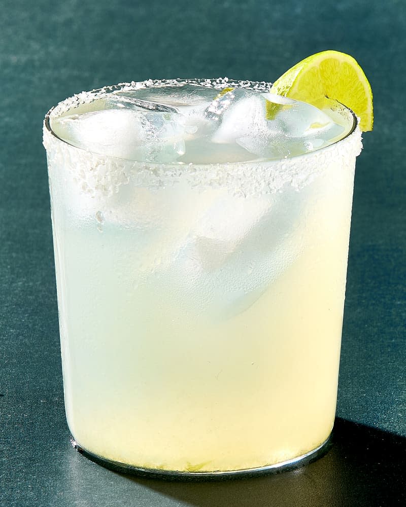 head on shot of a single margarita in a rocks glass, with a salted rim and a lime wedge.