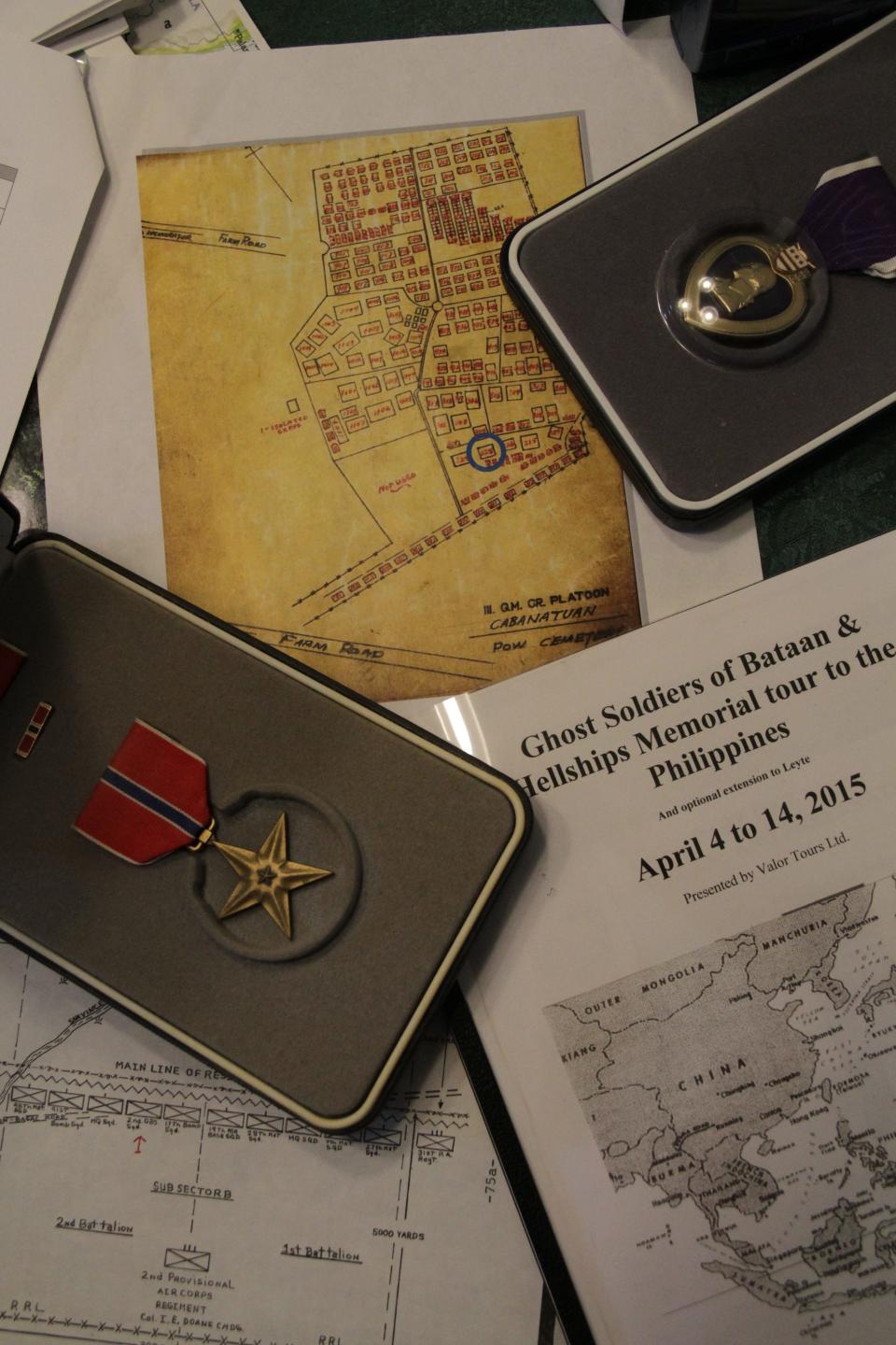 A 2015 file photo shows a Bronze Star and a Purple Heart among documents collected by John McConnell while researching the death of his brother Henry J. McConnell. At top center is a map of the Japanese prison camp where Henry was first buried.