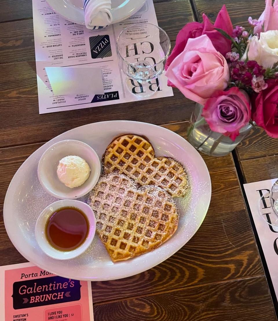 Two heart shaped buttermilk waffles with whipped butter, powdered sugar and maple syrup, available as part of Porta's 2024 Galentine's Day Brunch.