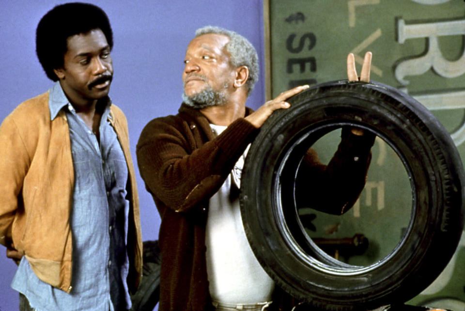 Demond Wilson and Redd Foxx stand with a tire