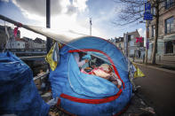 Two men share a meal in a makeshift tent camp outside the Petit Chateau reception center in Brussels, Tuesday, Jan. 17, 2023. Many refugees and asylum-seekers are literally left out in the cold for months as the European Union fails to get its migration system working properly. And most talk is about building fences and repatriation instead of working to improve a warm embrace for people fleeing nations like Afghanistan where the Taliban has taken over. (AP Photo/Olivier Matthys)