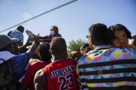 Araselli Zamora from San Antonio hands resources including food, clothing and baby carriers to a group of migrants early Friday, Sept. 17, 2021, in Ciudad Acuña, Mexico. Haitians crossed the Rio Grande freely and in a steady stream, going back and forth between the U.S. and Mexico through knee-deep water with some parents carrying small children on their shoulders. Unable to buy supplies in the U.S., they returned briefly to Mexico for food and cardboard to settle, temporarily at least, under or near the bridge in Del Rio, a city of 35,000 that has been severely strained by migrant flows in recent months. (Marie D. De Jesús/Houston Chronicle via AP)