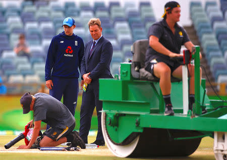 Cricket - Ashes test match - Australia v England - WACA Ground, Perth, Australia, December 18, 2017. England's captain Joe Root stands with former Australian cricketer Shane Warne as a groundsman uses a blower in an attempt to dry the pitch during a rain delay on the fifth day of the third Ashes cricket test match. REUTERS/David Gray