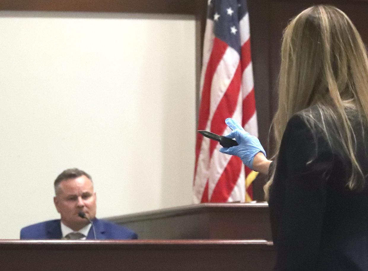 Assistant State Attorney Sarah Thomas holds the knife used in a March 2021 stabbing as Shane Jackson testifies Thursday during his trial on charges of aggravated battery causing great bodily harm.