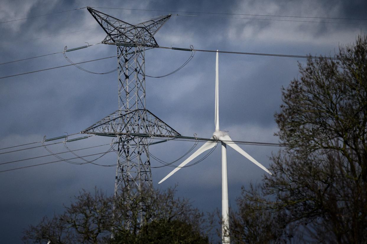 This photograph taken on January 17, 2023 in Campbon, western France, shows a high voltage line in front of a windmill. (Photo by LOIC VENANCE / AFP) (Photo by LOIC VENANCE/AFP via Getty Images)