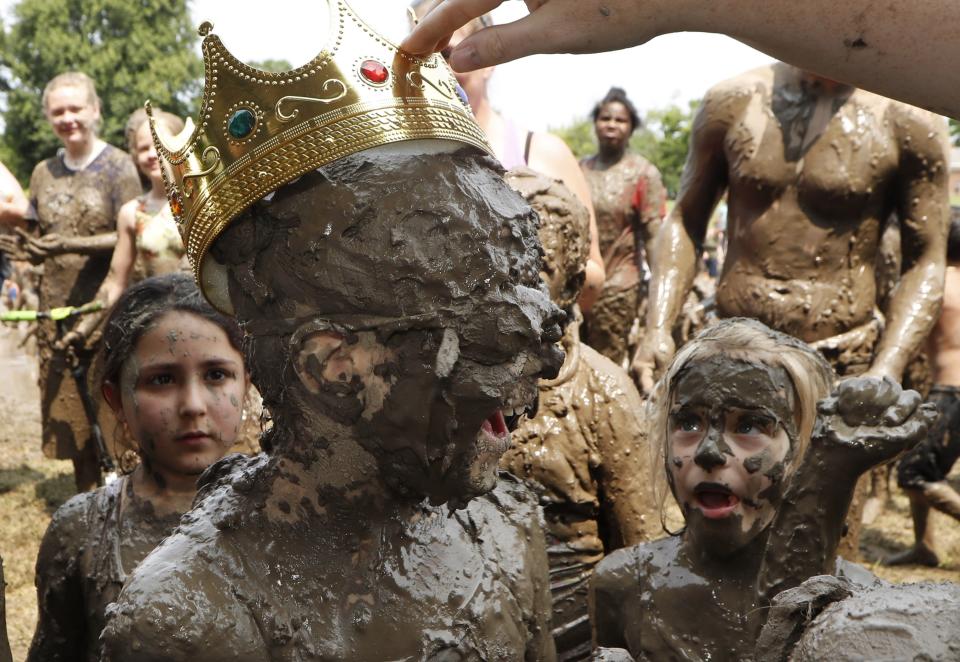 Kids watch as Riley Tulgetske is crowned Mud Day Queen during Mud Day at the Nankin Mills Park, Tuesday, July 9, 2019, in Westland, Mich. The annual day is for kids 12 years old and younger. While parents might be welcome, this isn't an event meant for teens or adults. It's all about the kids having some good, unclean fun during their summer break and is sponsored by the Wayne County Parks. (AP Photo/Carlos Osorio)
